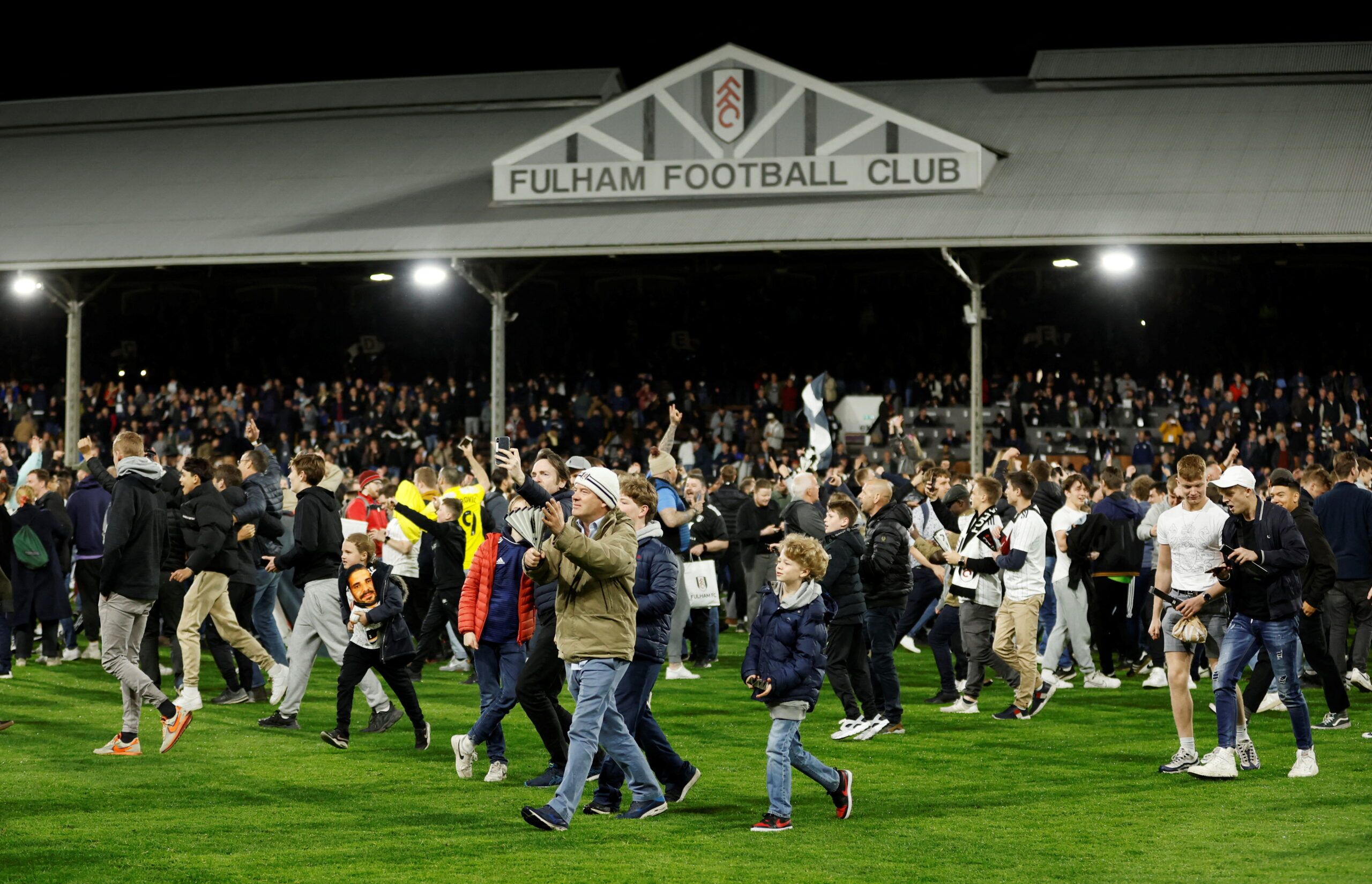 Soccer Football - Championship - Fulham v Preston North End - Craven Cottage, London, Britain - April 19, 2022 Fulham fans celebrate on the pitch after being promoted to the Premier League  Action Images via Reuters/Peter Cziborra  EDITORIAL USE ONLY. No use with unauthorized audio, video, data, fixture lists, club/league logos or 