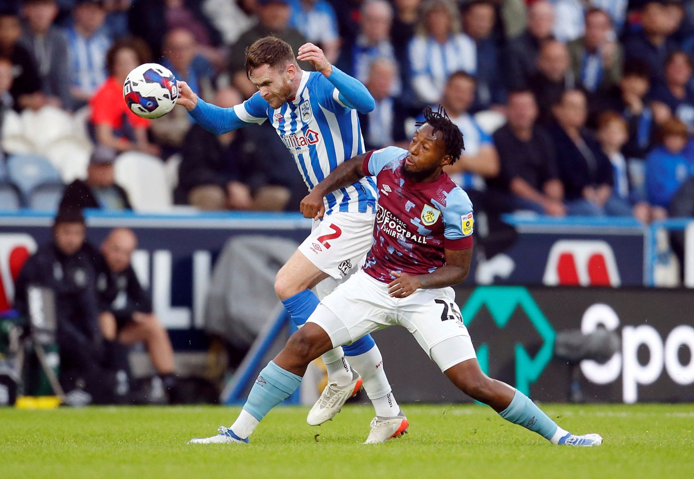 Soccer Football - Championship - Huddersfield Town v Burnley - John Smith's Stadium, Huddersfield, Britain - July 29, 2022  Huddersfield Town's Ollie Turton in action with Burnley's Samuel Bastien  Action Images/Ed Sykes  EDITORIAL USE ONLY. No use with unauthorized audio, video, data, fixture lists, club/league logos or 
